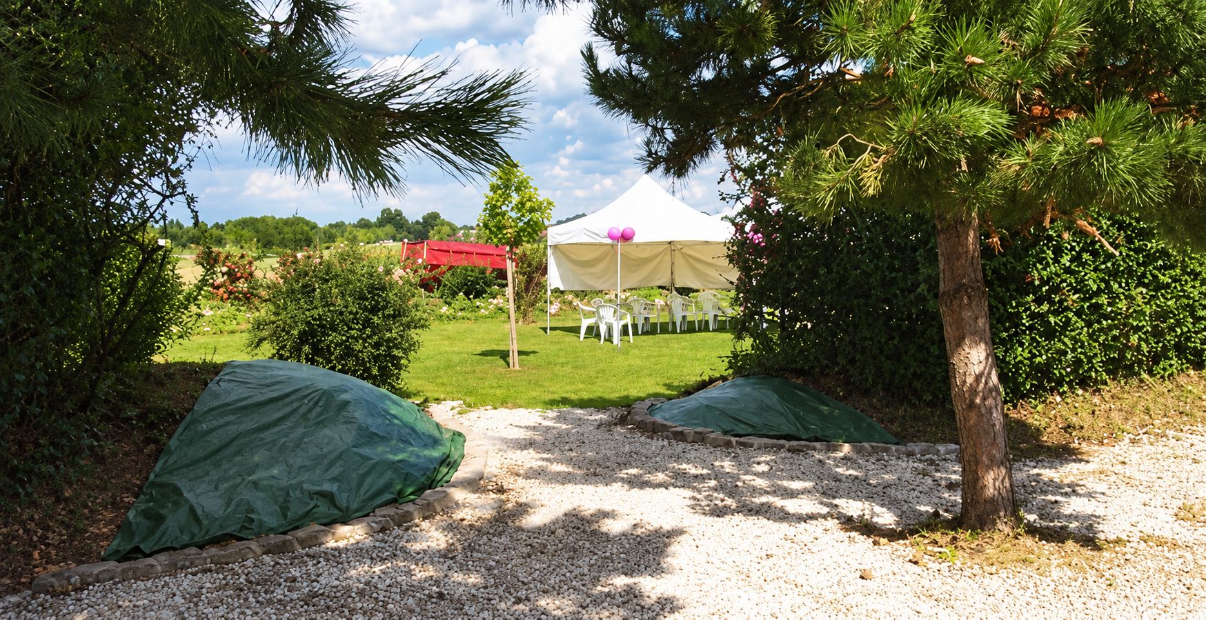 Chemin de gravier et tente de réception au fond d'un jardin calme