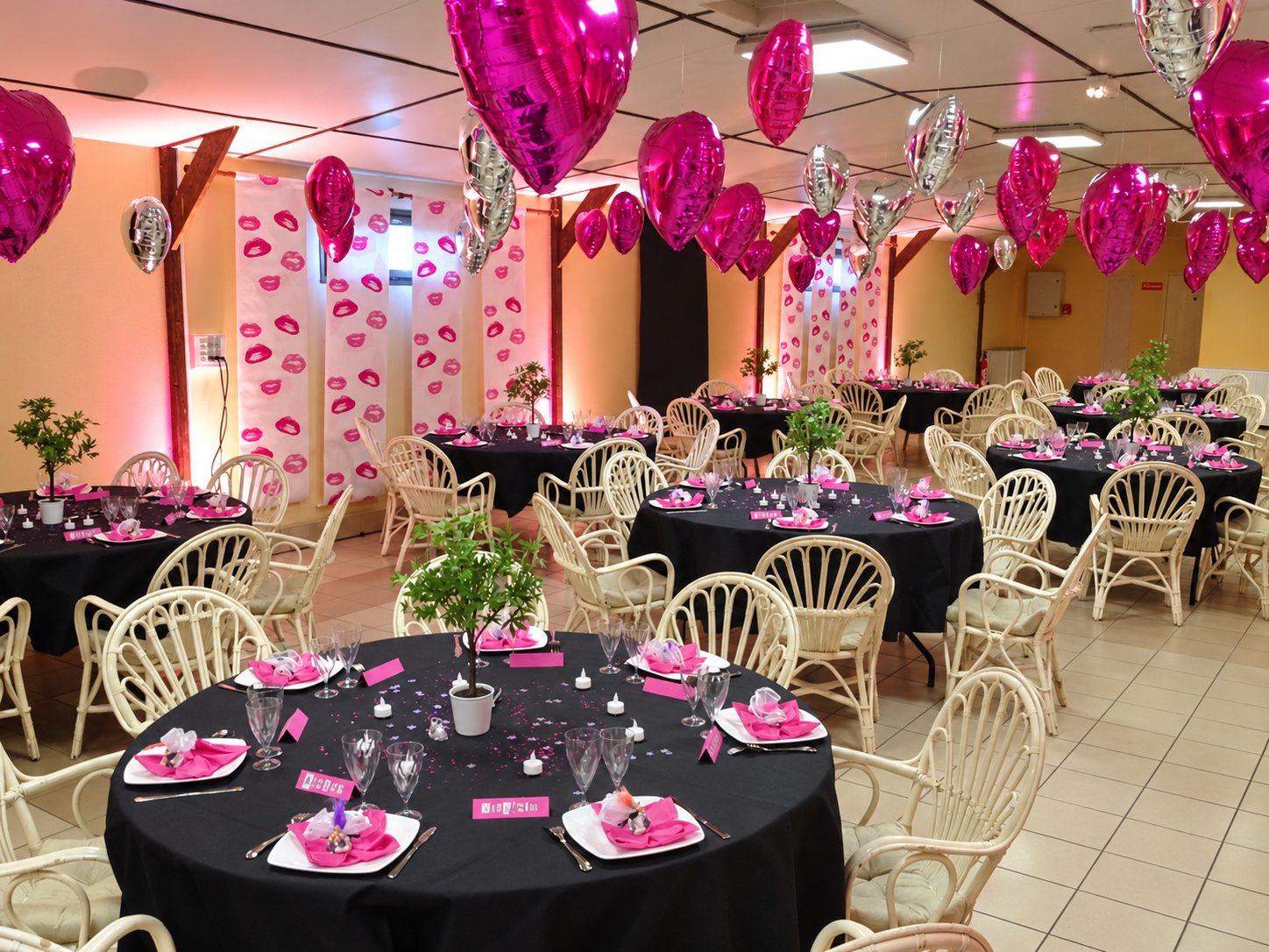 Salle de réception décorée de ballons en cœur, tables rondes dressées